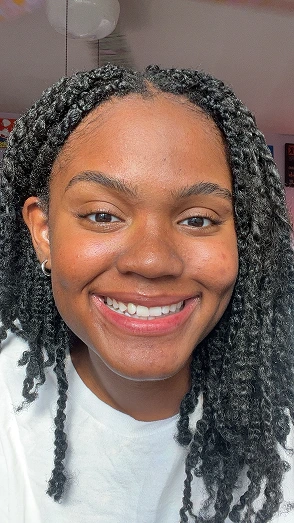 Person smiling with braided hair, wearing a white shirt.