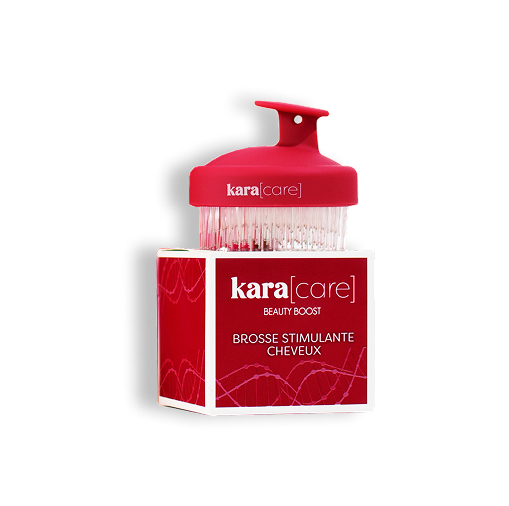 A red Kara Care scalp massager brush sitting on its red and white packaging box.