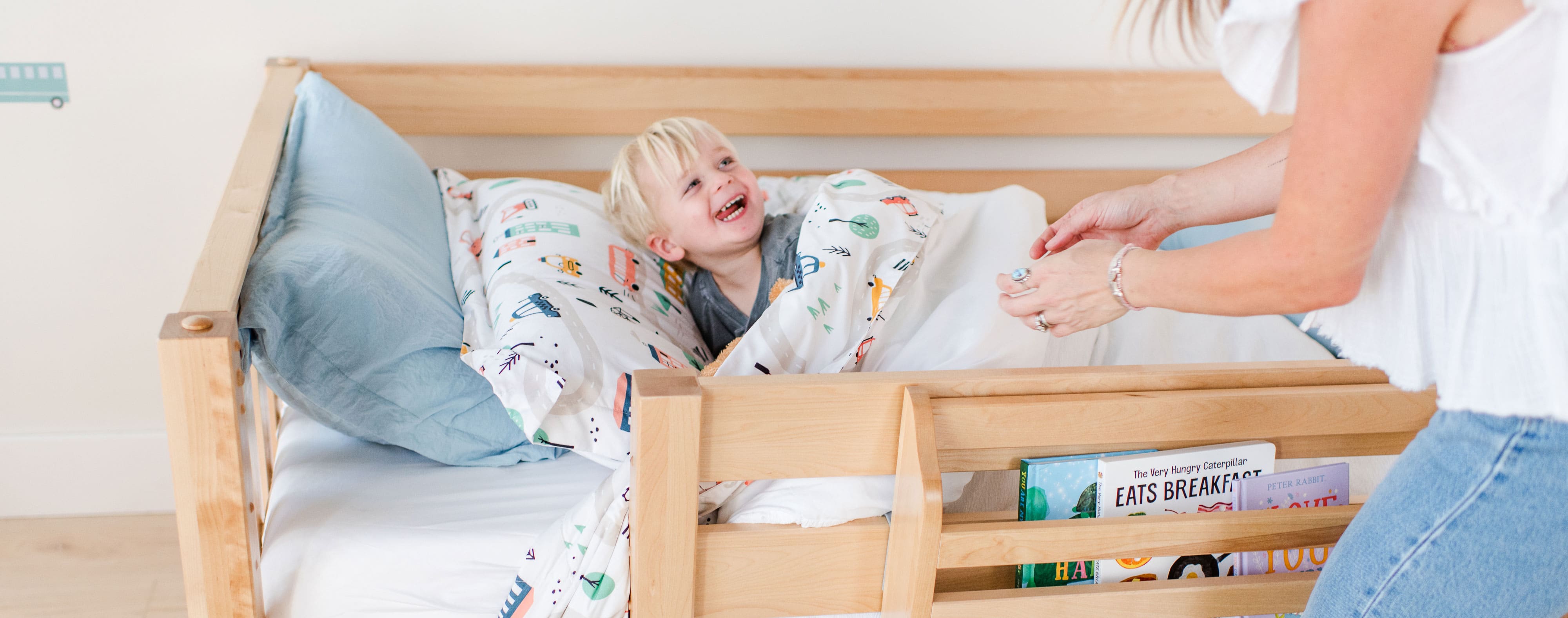 Little boy smiling in bed at his mother.