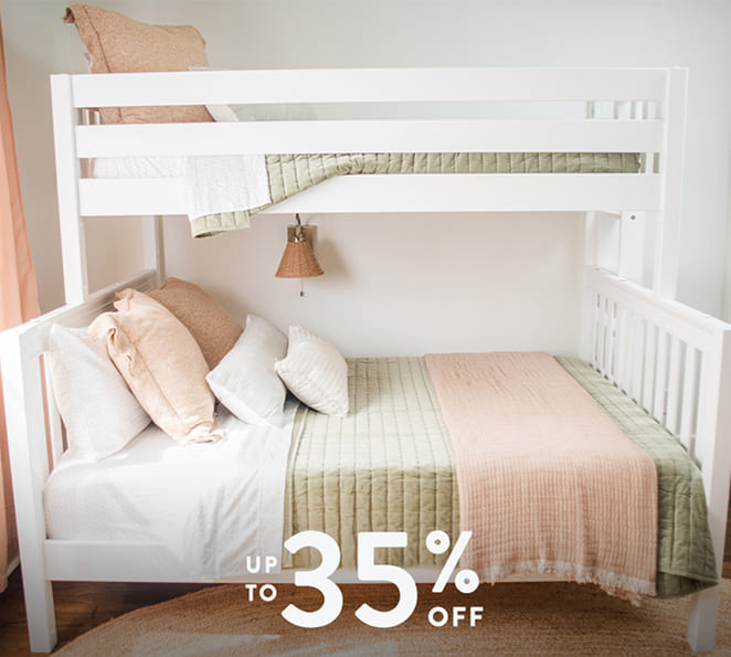 White wooden bunk bed in a bright kids' bedroom featuring a pastel green quilt, blush-pink throw and pillows, woven wall lamp, and prominent 'Up to 35% off' sale text overlay.