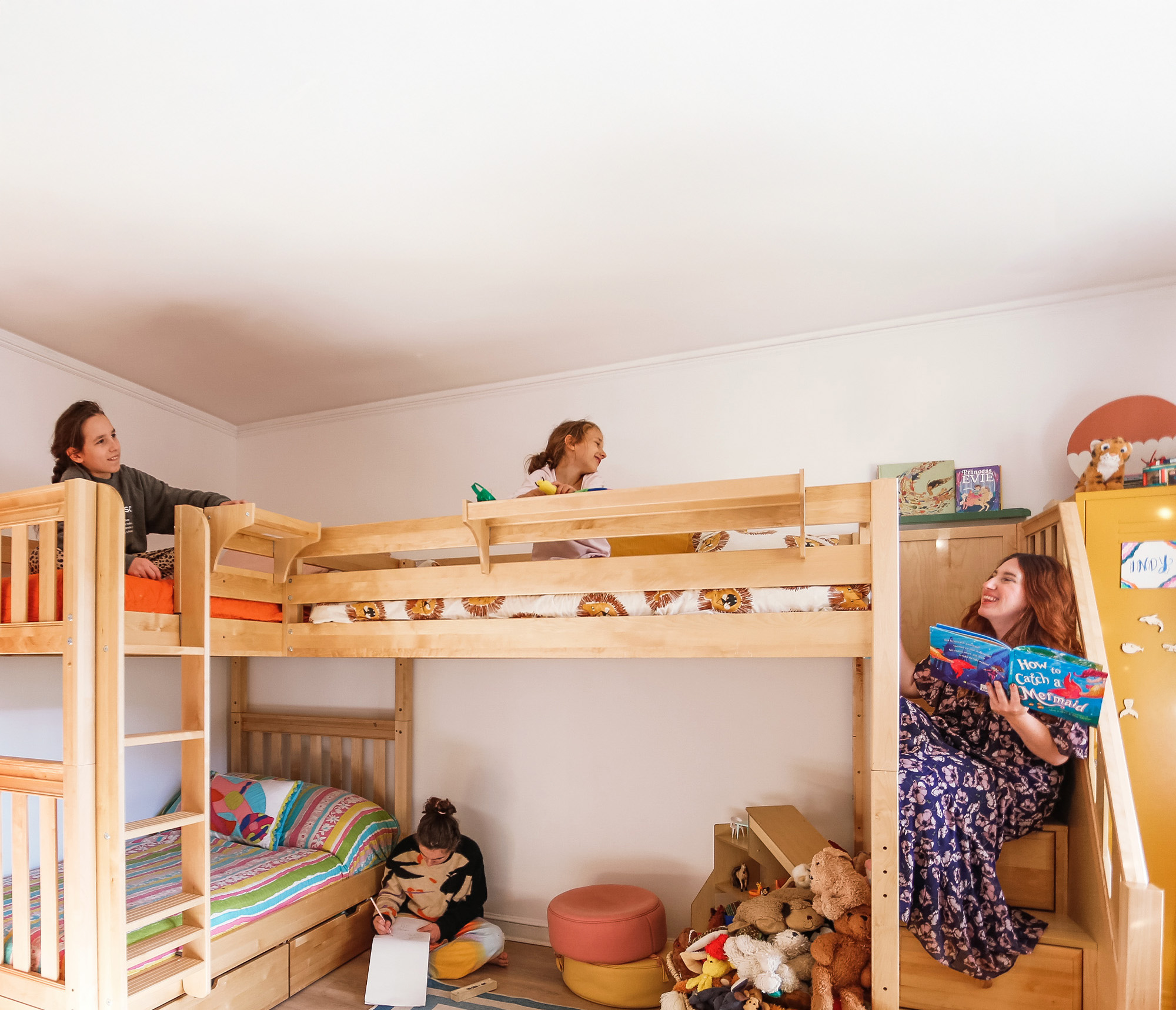 Children and a woman enjoying activities around a bunk bed in a cozy room.