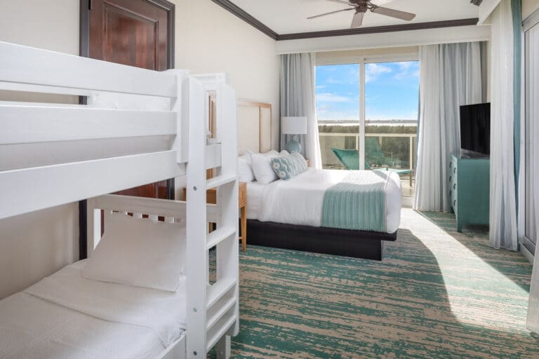 Hotel room with bunk beds, double bed, and balcony view.