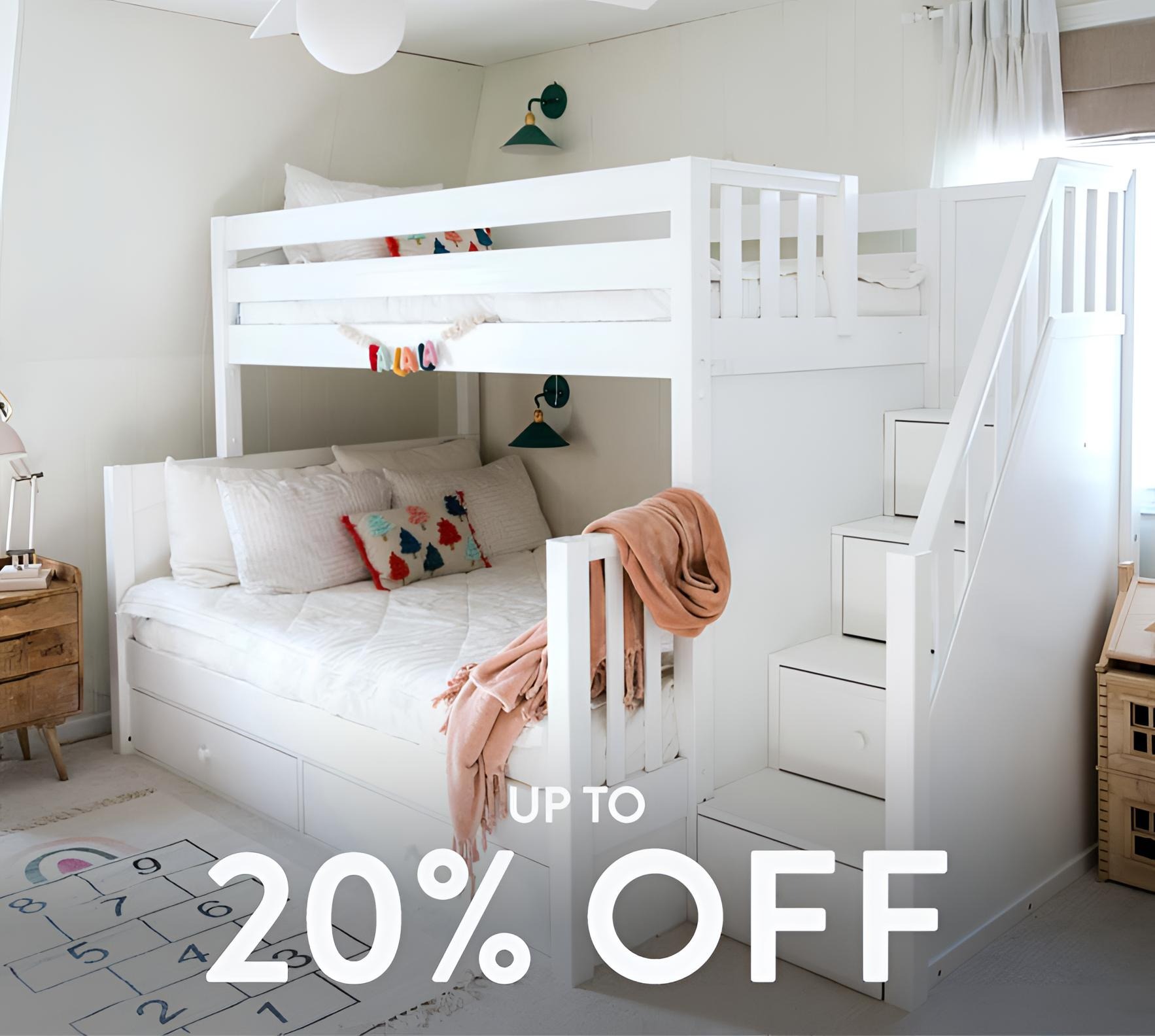 White wooden bunk bed with staircase storage and under-drawers in a bright kids' bedroom with decorative pillows and hopscotch rug — up to 20% off kids' bedroom furniture sale.
