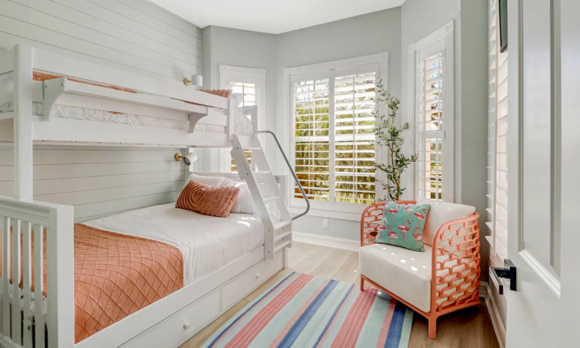 Bright bedroom with bunk bed, armchair, and striped rug.