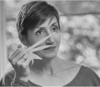 Person holding paper strips near face, black and white photo.