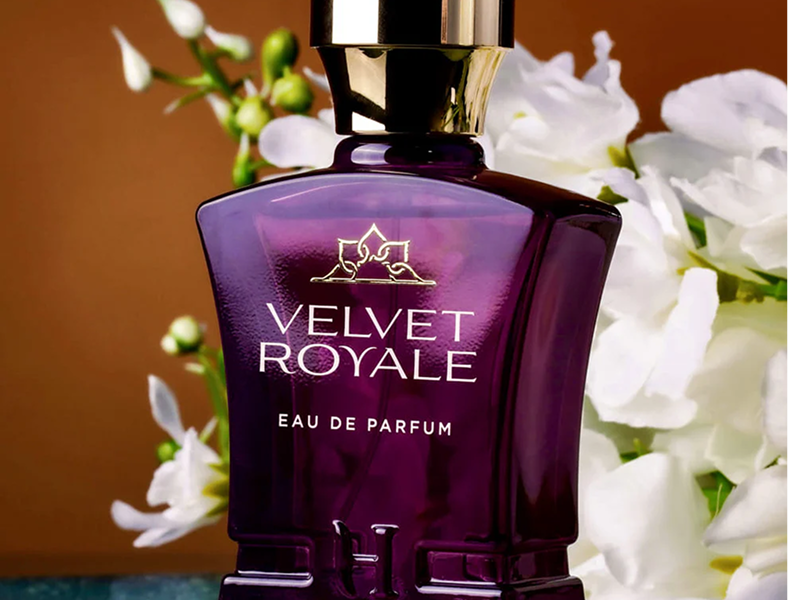 Purple perfume bottle labeled 'Velvet Royale' with white flowers in the background.