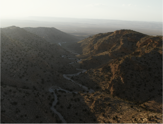Aerial view of a desert valley with winding paths and rocky hills.