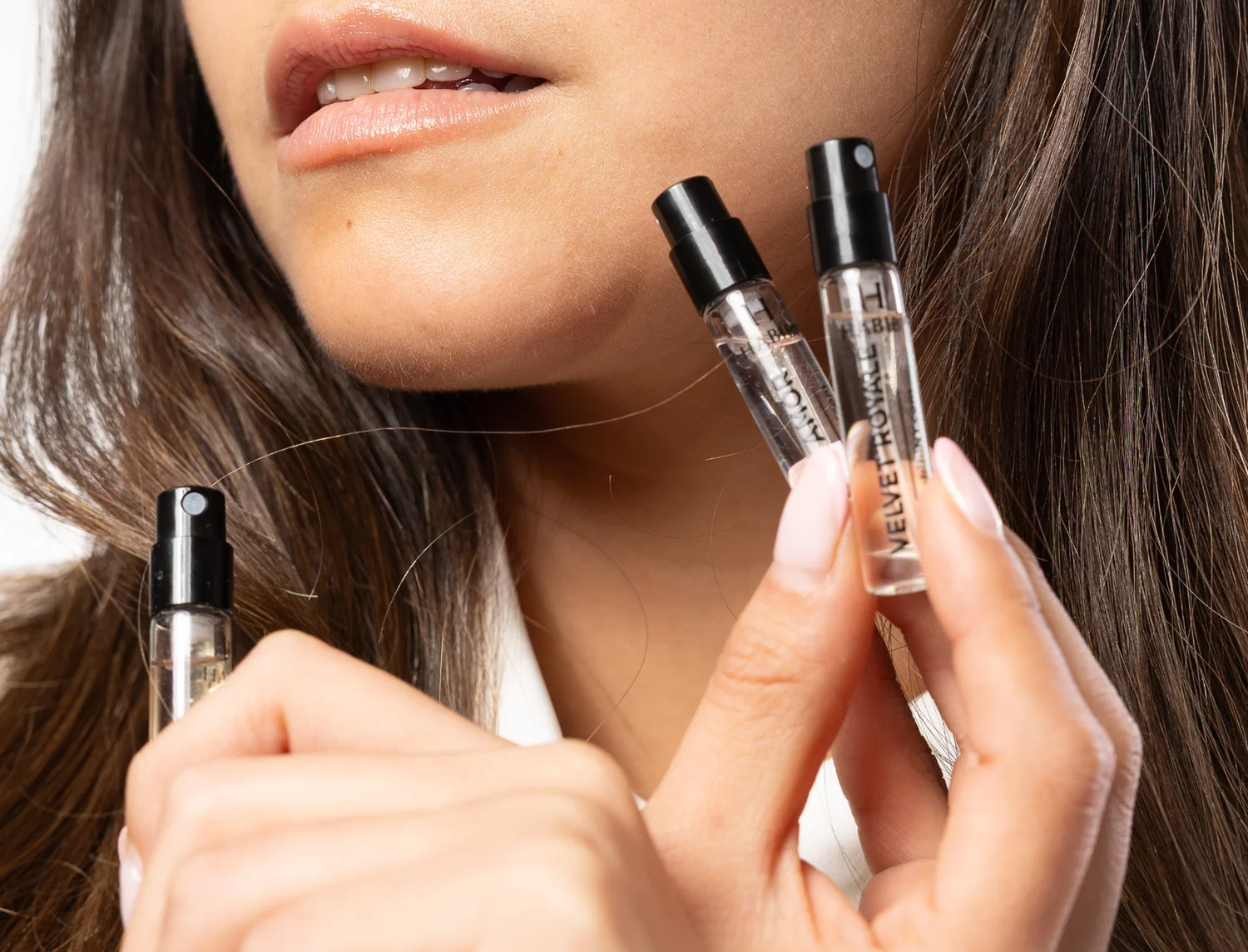 Close-up of a person holding small spray bottles near their face.