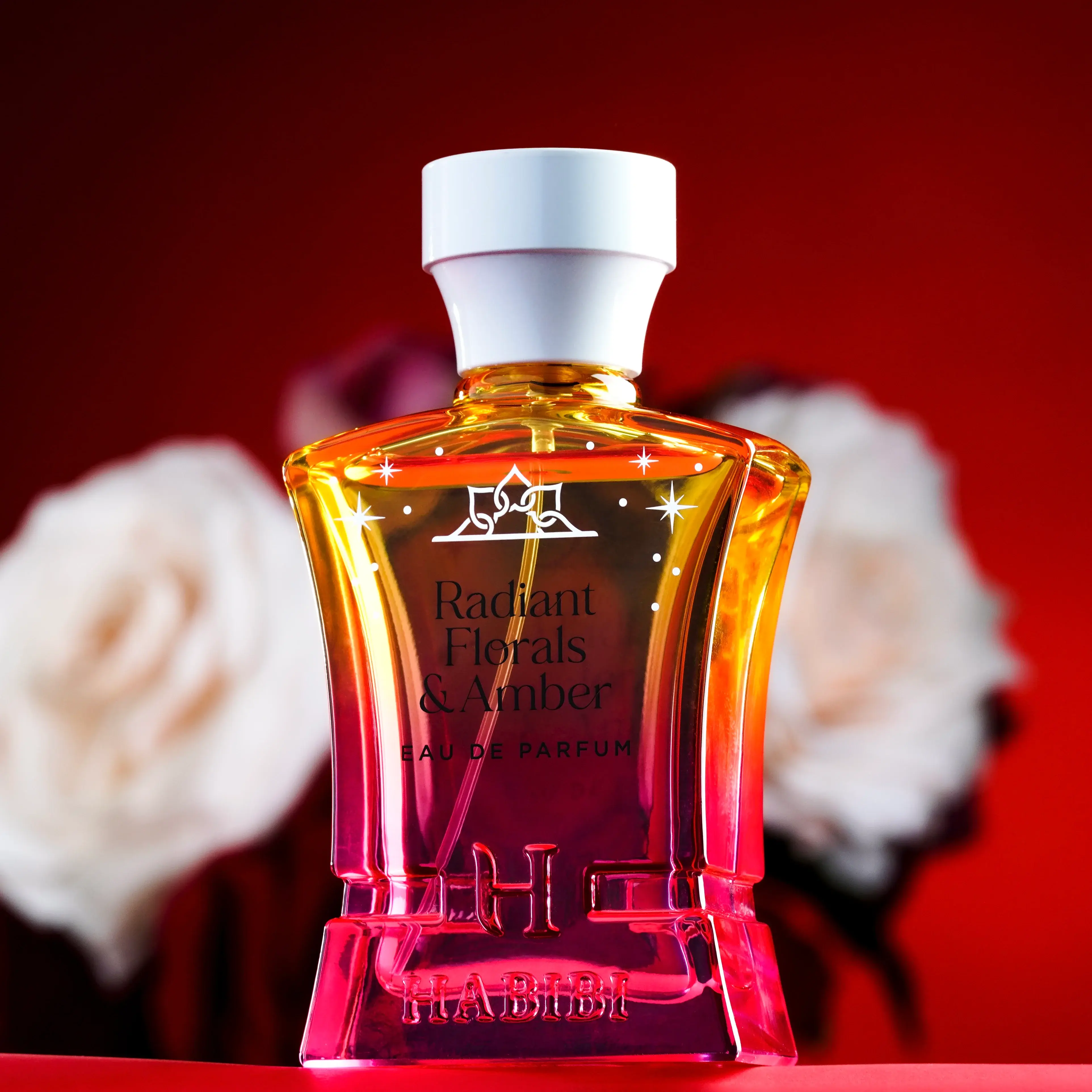 Perfume bottle labeled 'Radiant Florals & Amber' with flowers in the background.
