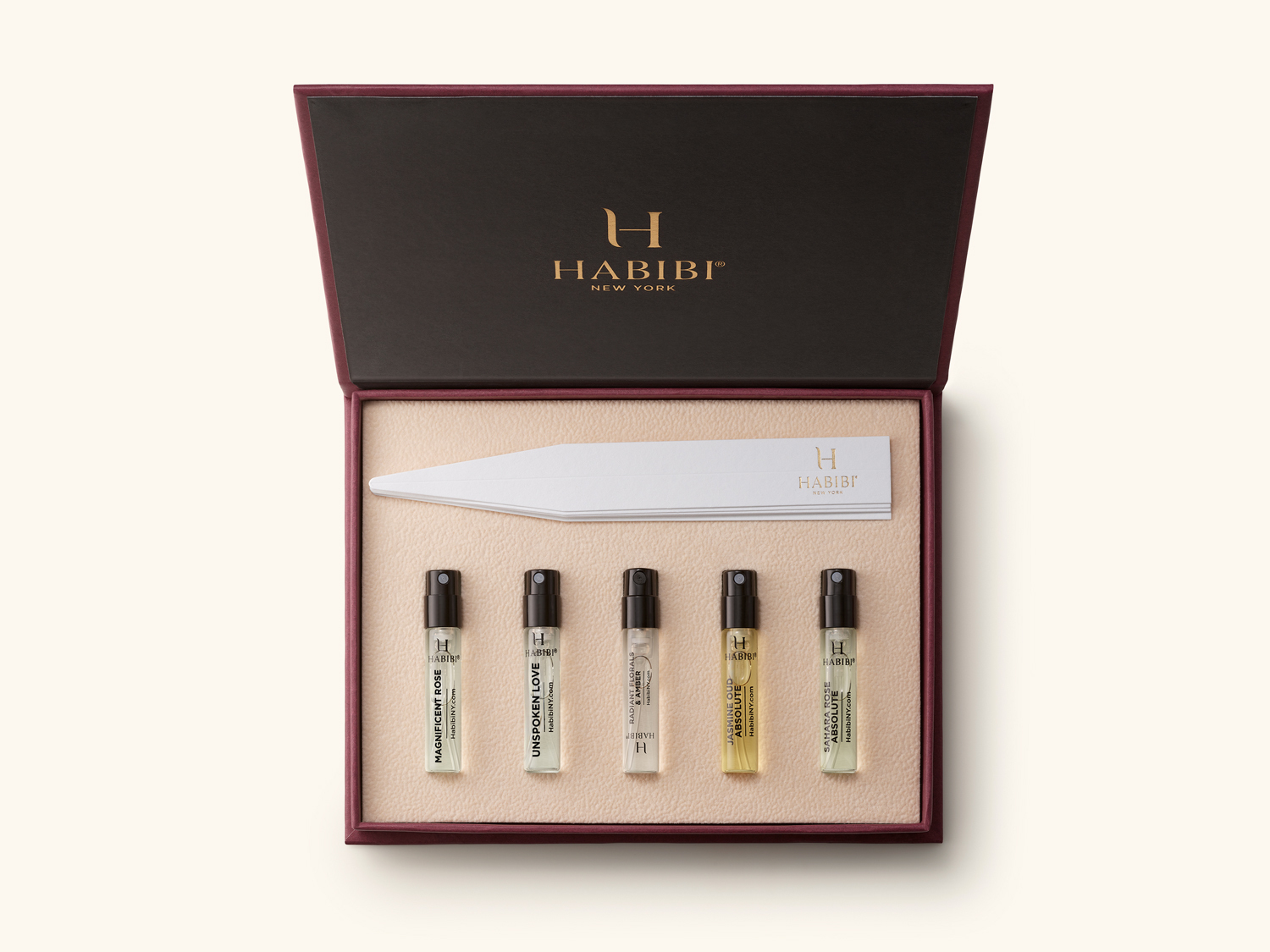 Open box with five small perfume spray bottles and paper strips.