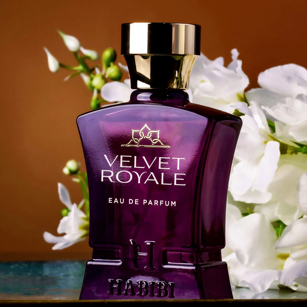 Purple perfume bottle labeled 'Velvet Royale' with white flowers in the background.