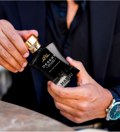 Person holding a black perfume bottle labeled 'Desert Oud.'