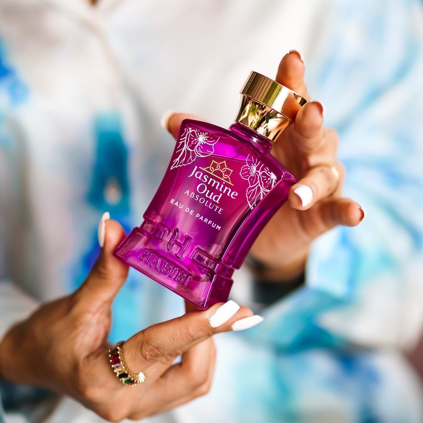 Person holding a purple perfume bottle labeled 'Jasmine Oud Absolute.'