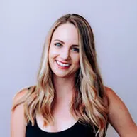 Person with long blonde hair smiling against a plain background.