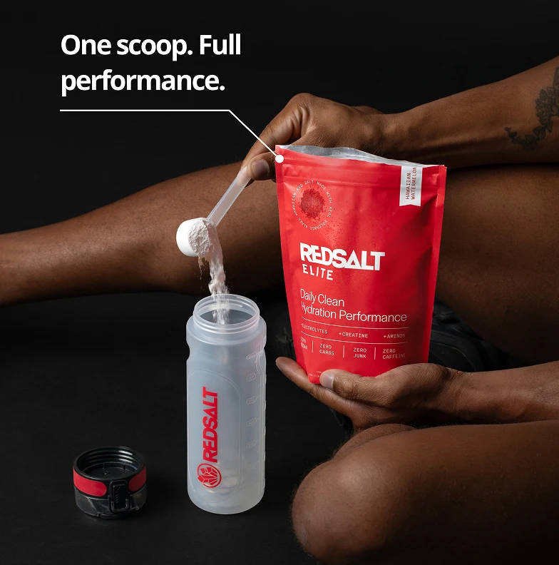 Person scooping powder into a bottle from a red package labeled 'RedSalt Elite.'