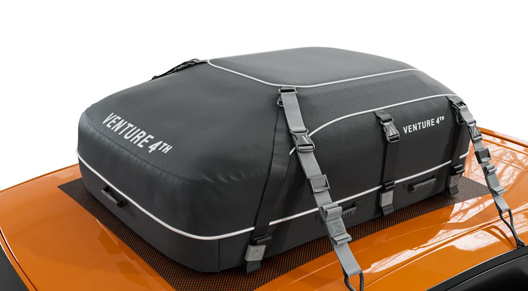 Black roof cargo bag labeled 'Venture 4th' on an orange car.