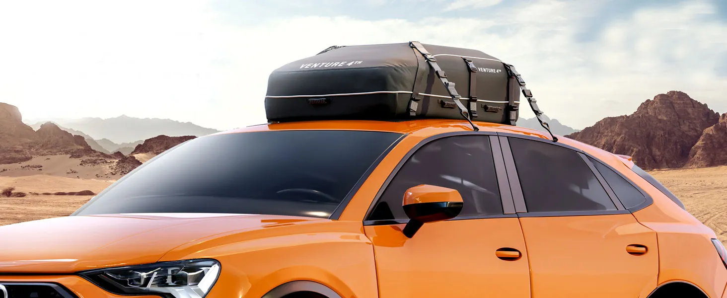 Orange car with roof cargo bag in desert landscape.