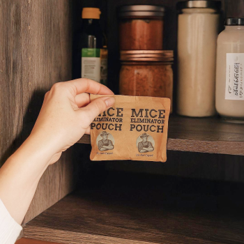 Hand placing a mice eliminator pouch in a wooden cupboard with jars.