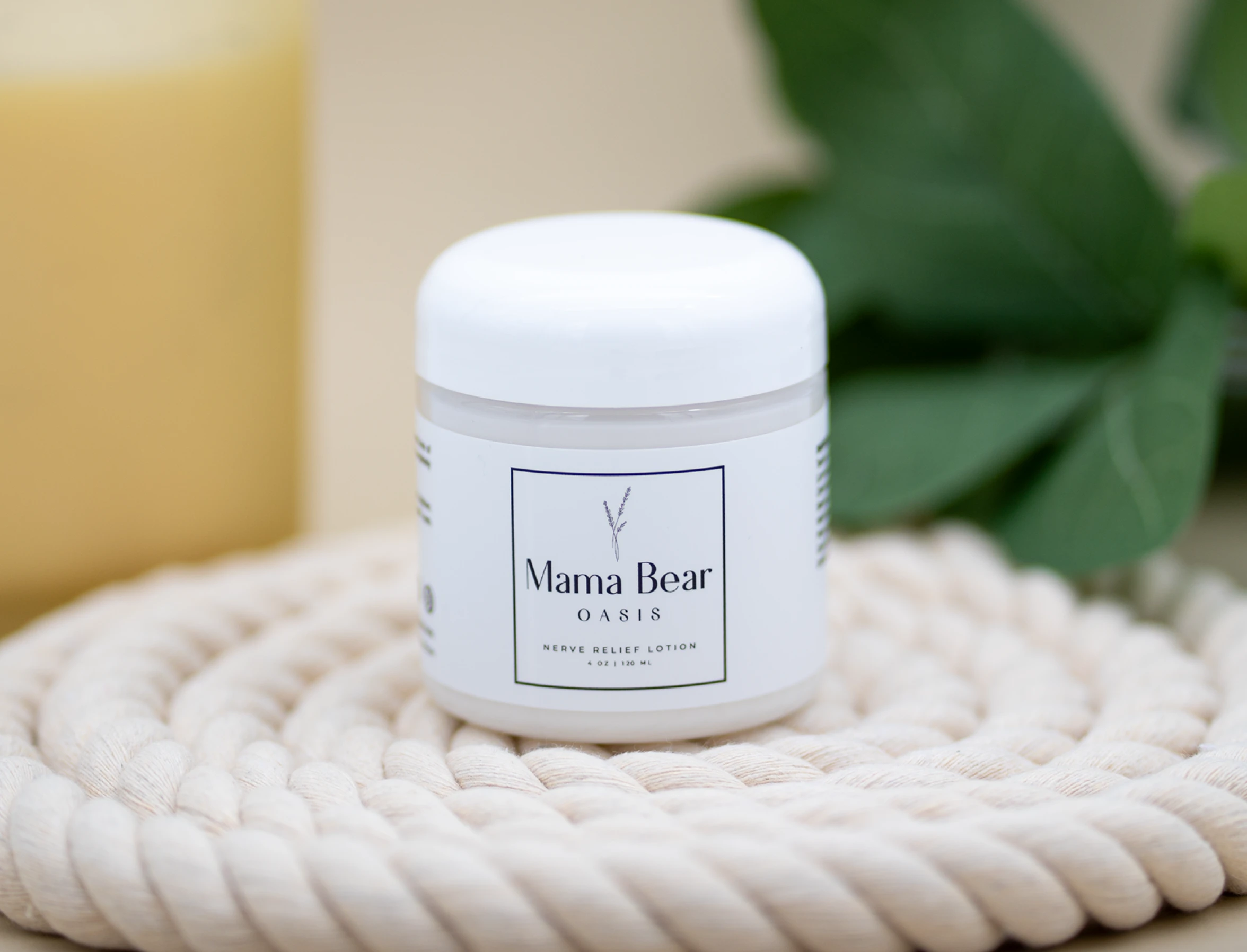 White jar of 'Mama Bear Oasis' lotion on a coiled rope mat.