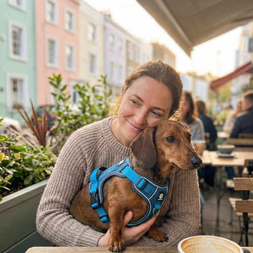 Person wearing a gray coat with a bright pink shoulder bag.