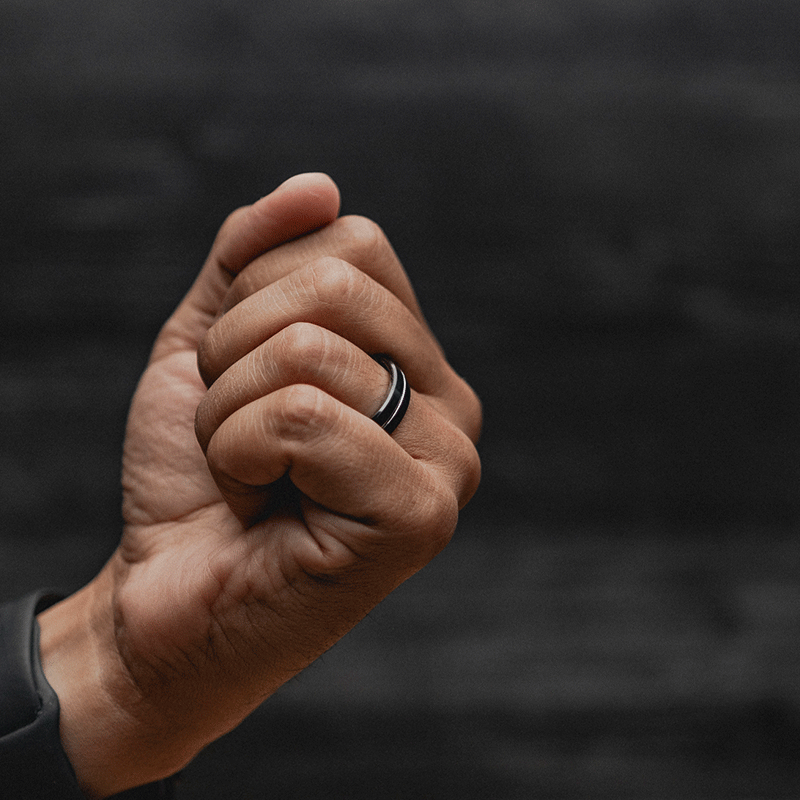 Close-up of a hand with a black ring, fist closed.