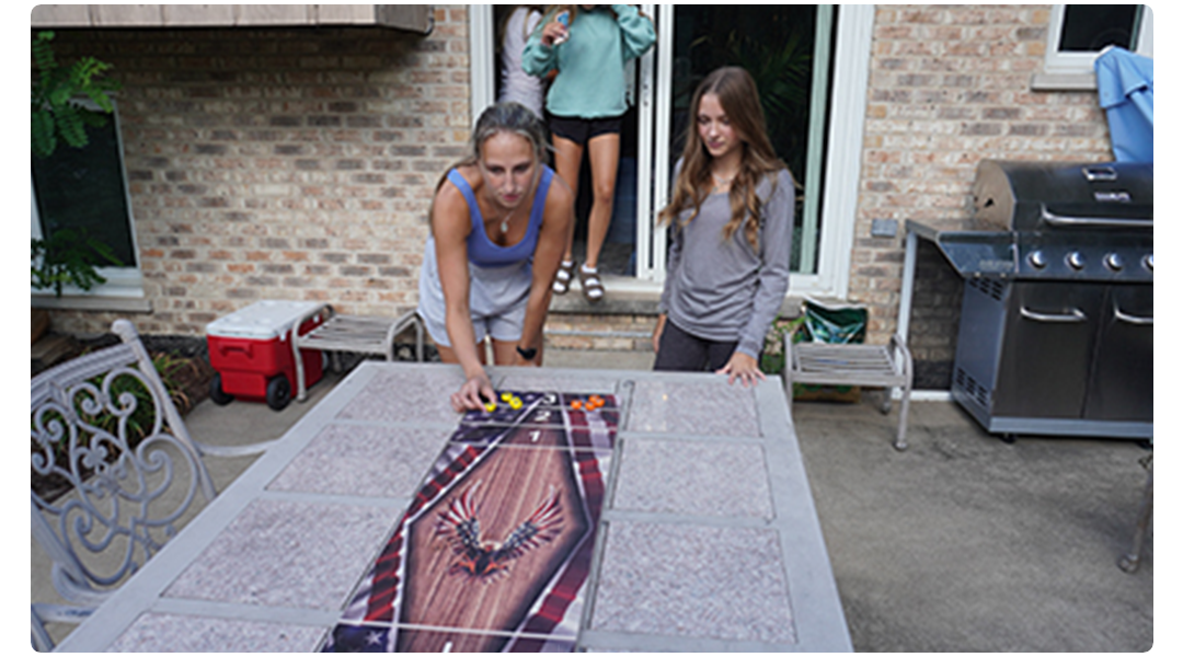 People play a board game on an outdoor patio table.