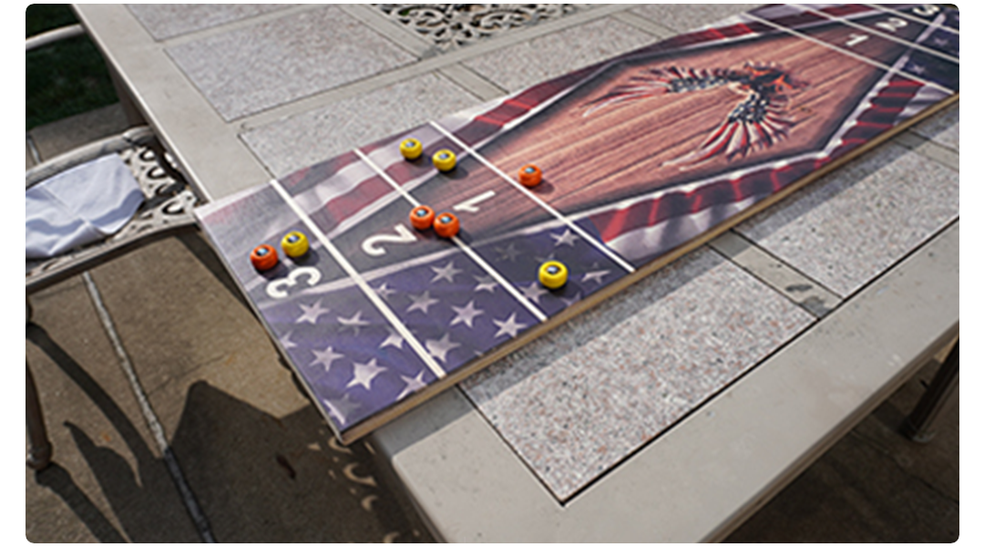 Shuffleboard on a table with star patterns and colored pucks.