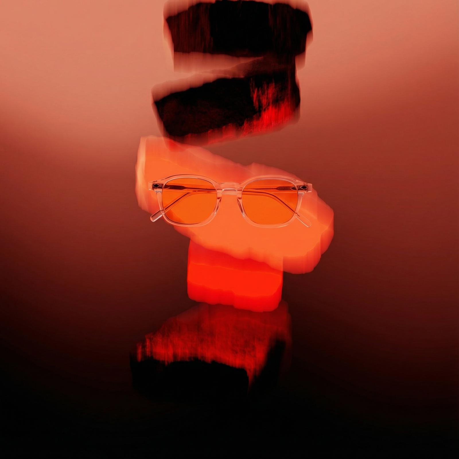 Orange-tinted glasses on blurred red and black abstract background.