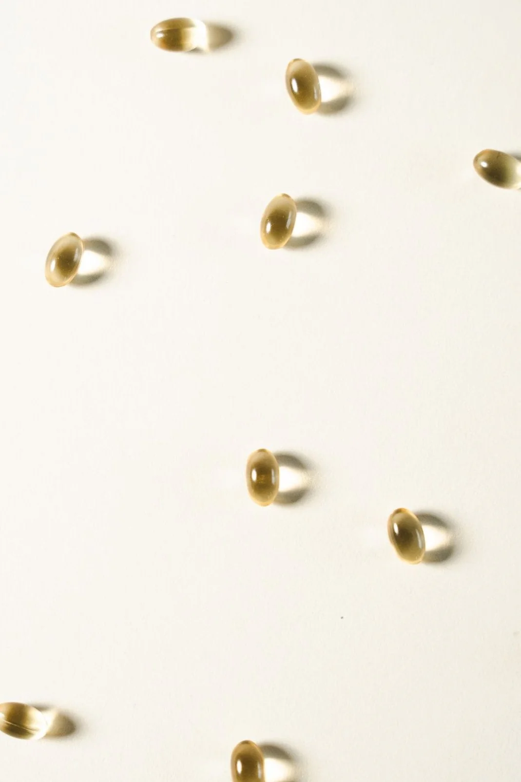 Scattered brown gel capsules on a white background.