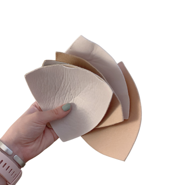 Hand holding several beige fabric swatches.