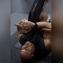 Phil Heath lying on his back stretching his leg with a black CastleFlexx strap
