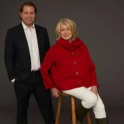 Martha Stewart seated on a stool beside a man in a suit