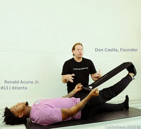 CastleFlexx founder Dan Castle demonstrating a CastleFlexx stretch with an athlete lying on a physical therapy table