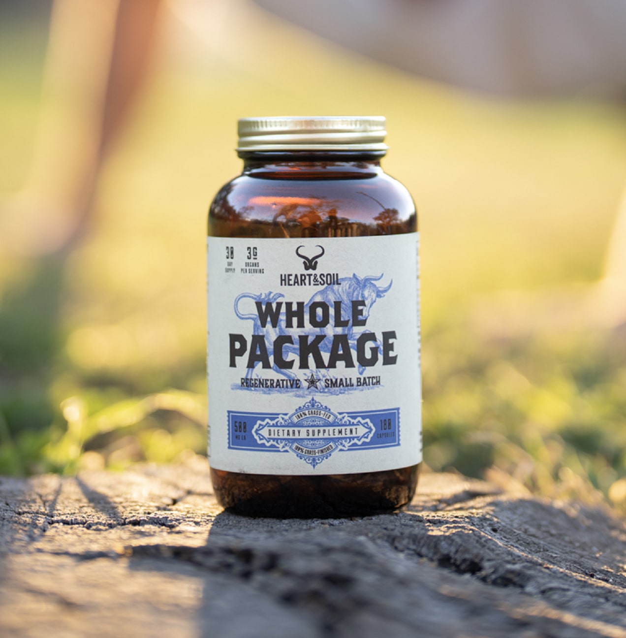 A bottle labeled 'Whole Package' on a tree stump outdoors.