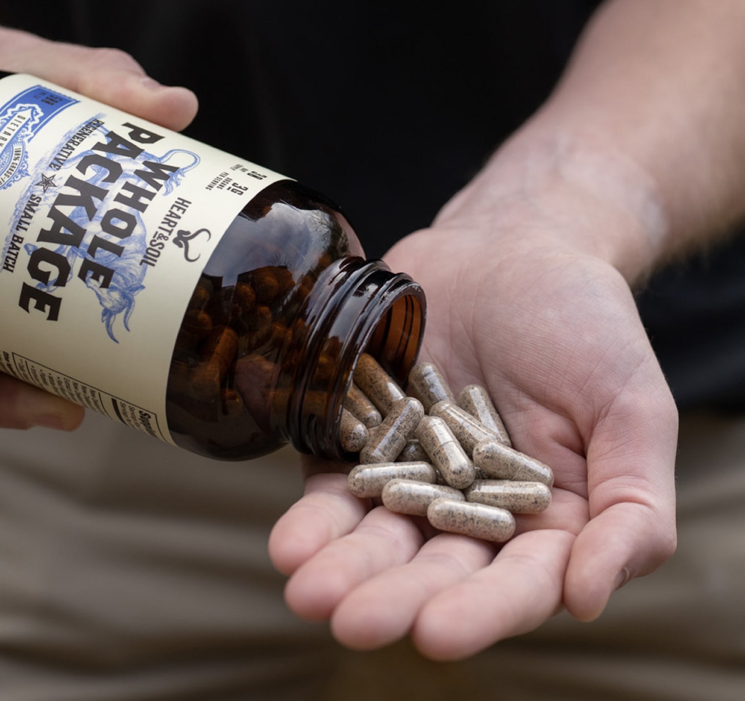 Person holding a bottle, pouring capsules into their hand.