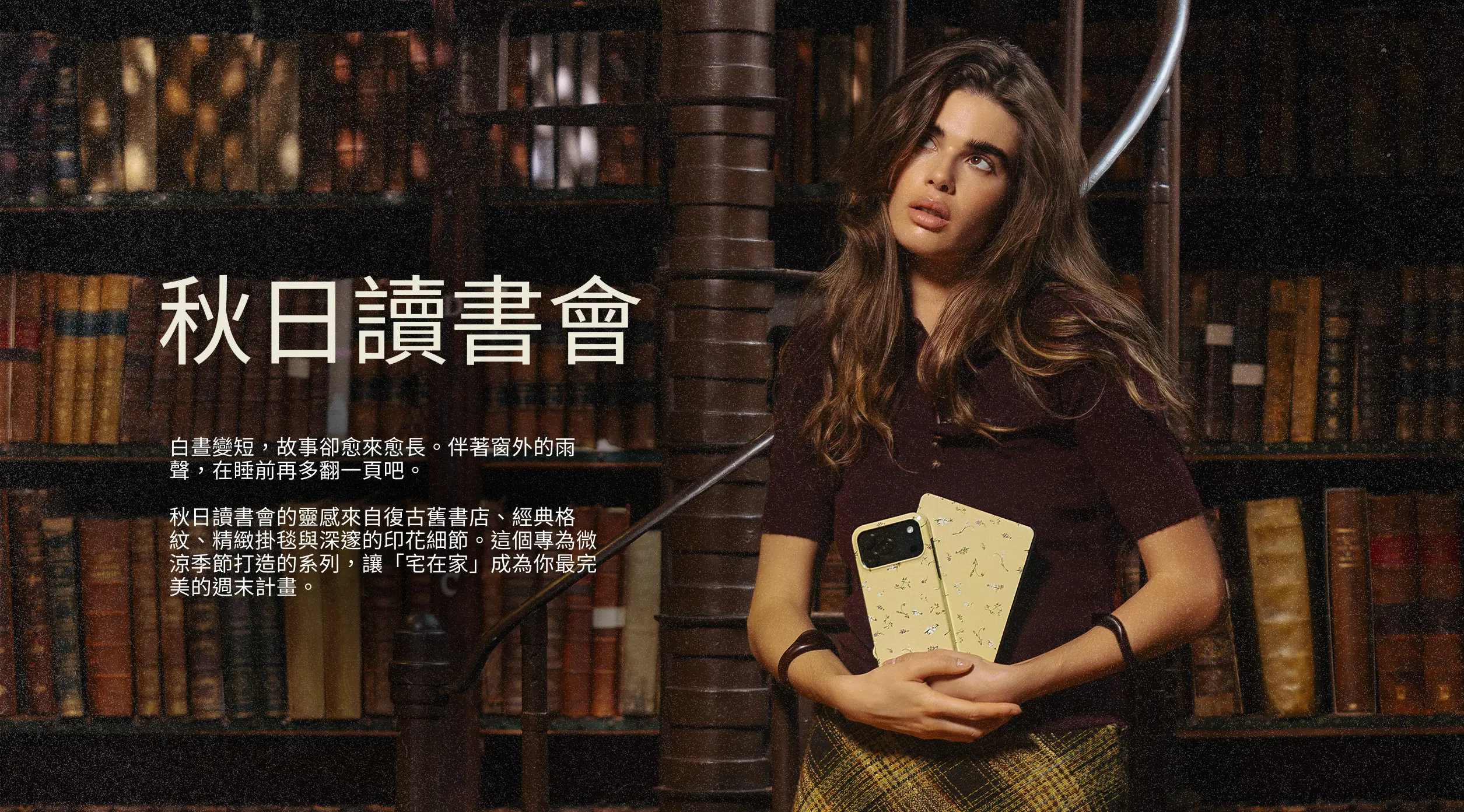 A woman in a library holds a patterned phone case while looking up.