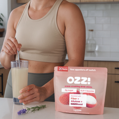 Person stirring a drink next to a package of lychee-flavored drink sticks.