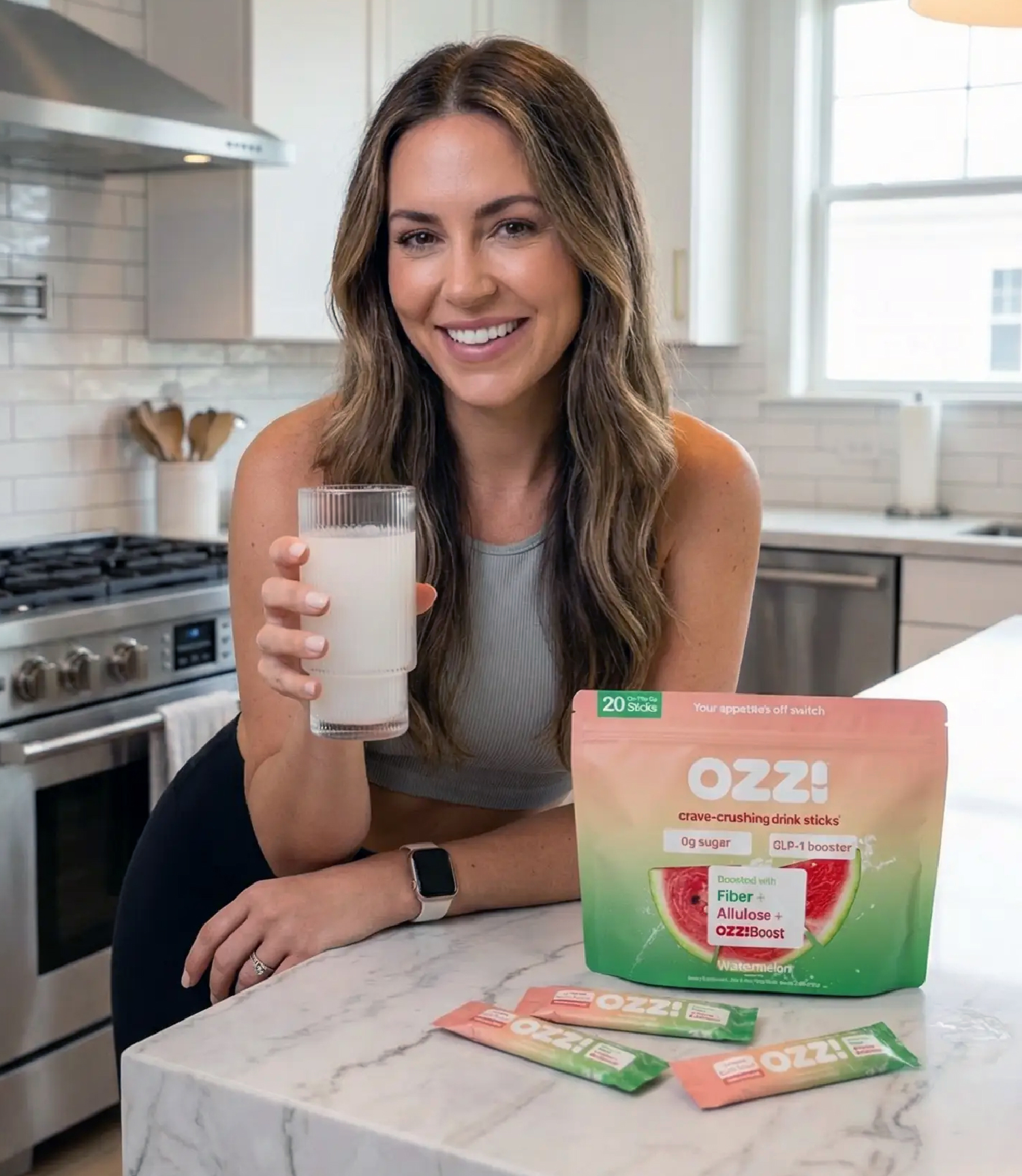 Person holding a glass next to drink packets on a kitchen counter.
