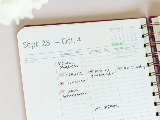 A close-up of a weekly planner with handwritten appointments and to-do lists for late September.