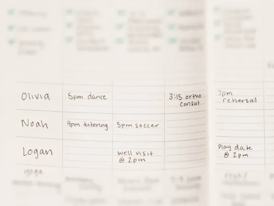 A close-up of a handwritten weekly planner showing a family's busy schedule of appointments and activities.