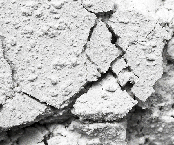Close-up of cracked, textured white surface resembling dried clay or plaster.
