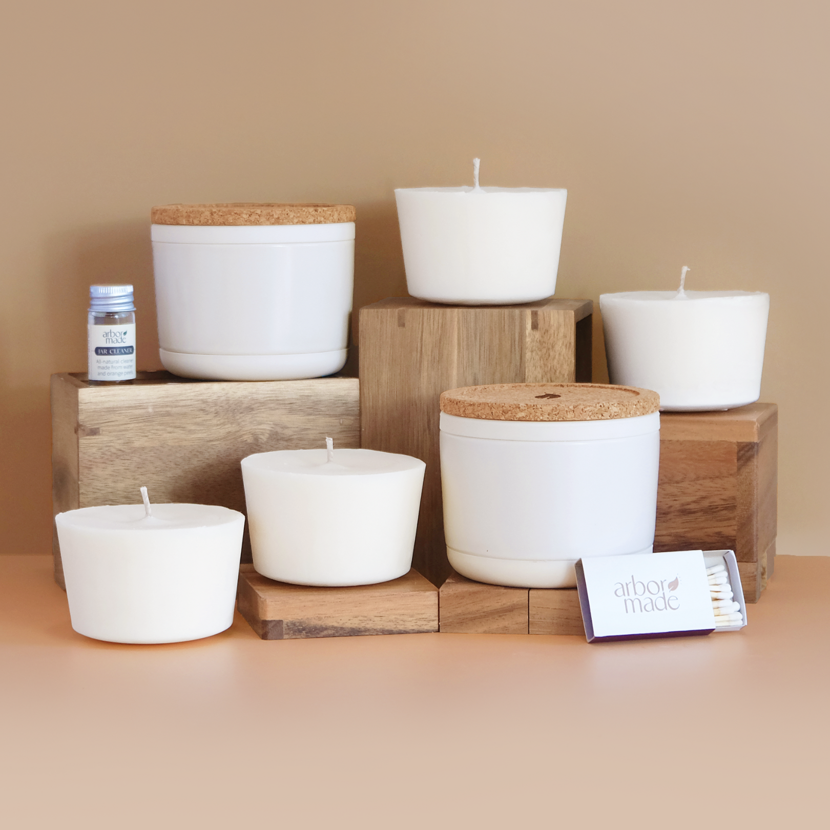 White candles and matchbox on wooden blocks with small jar.