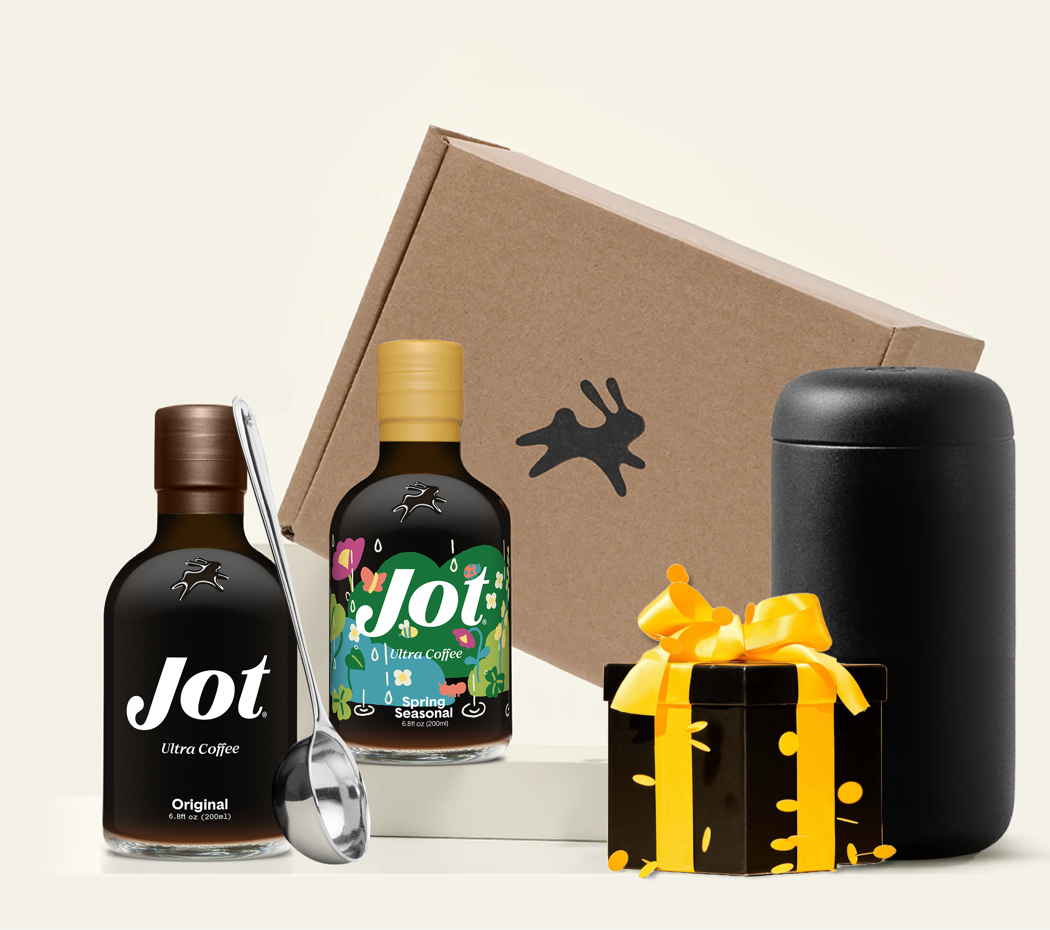Two bottles of Jot coffee concentrate, a ladle, canister, and gift boxes arranged on a white surface.
