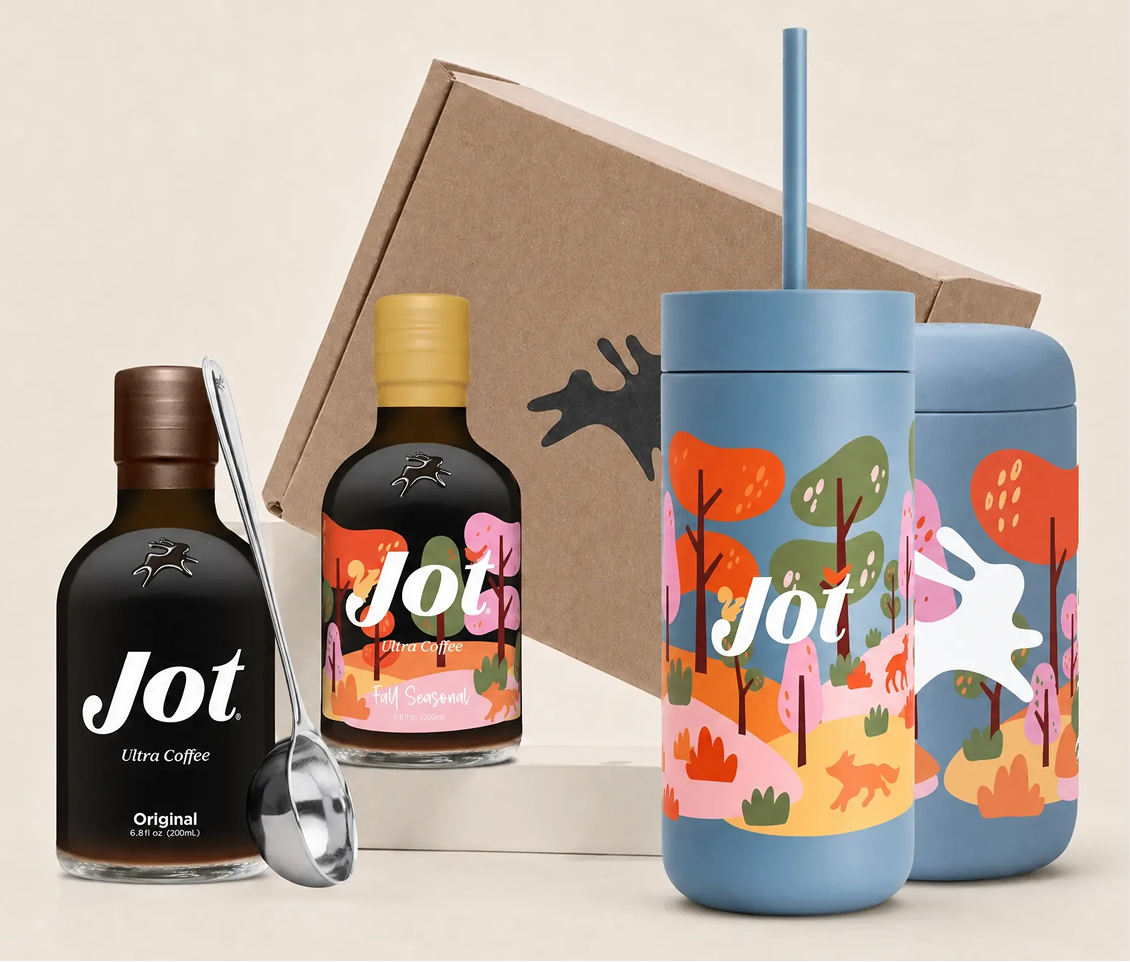 Two bottles of Jot coffee concentrate, a colorful tumbler, and a small ladle arranged for a product shot.