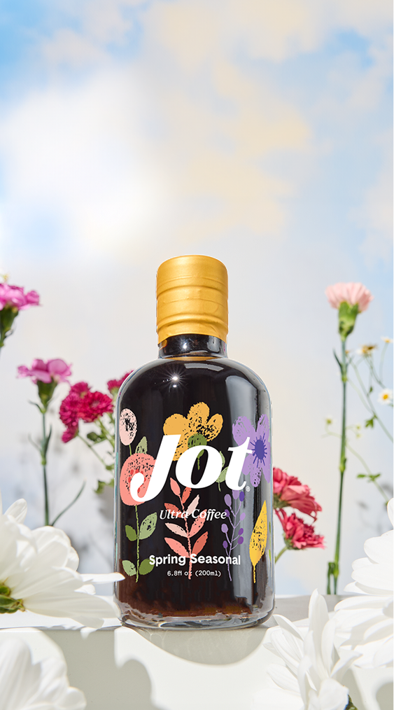 Bottle of Jot Ultra Coffee with floral design, surrounded by flowers.