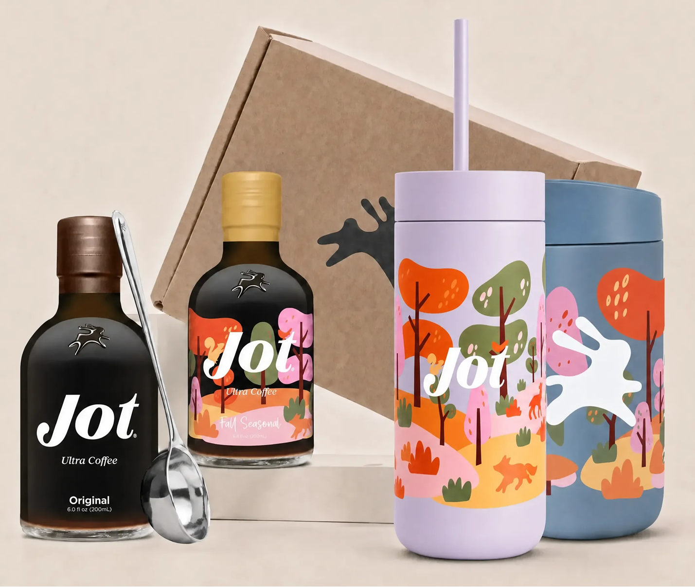 Two bottles of Jot coffee concentrate, a metal spoon, and two colorful tumblers with a forest design.