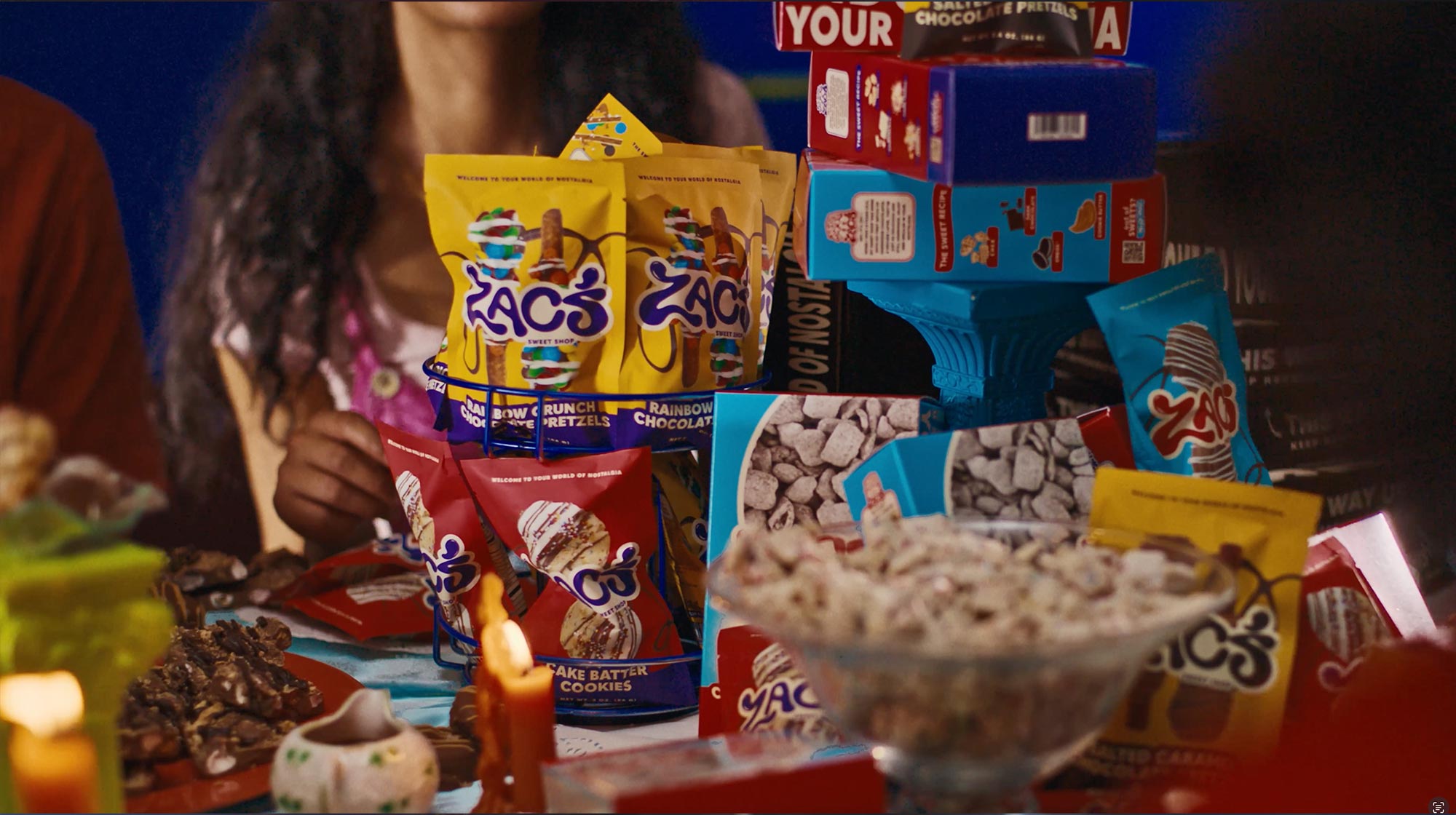 A table filled with a colorful assortment of Zac's Sweet Shop snacks in various packages.