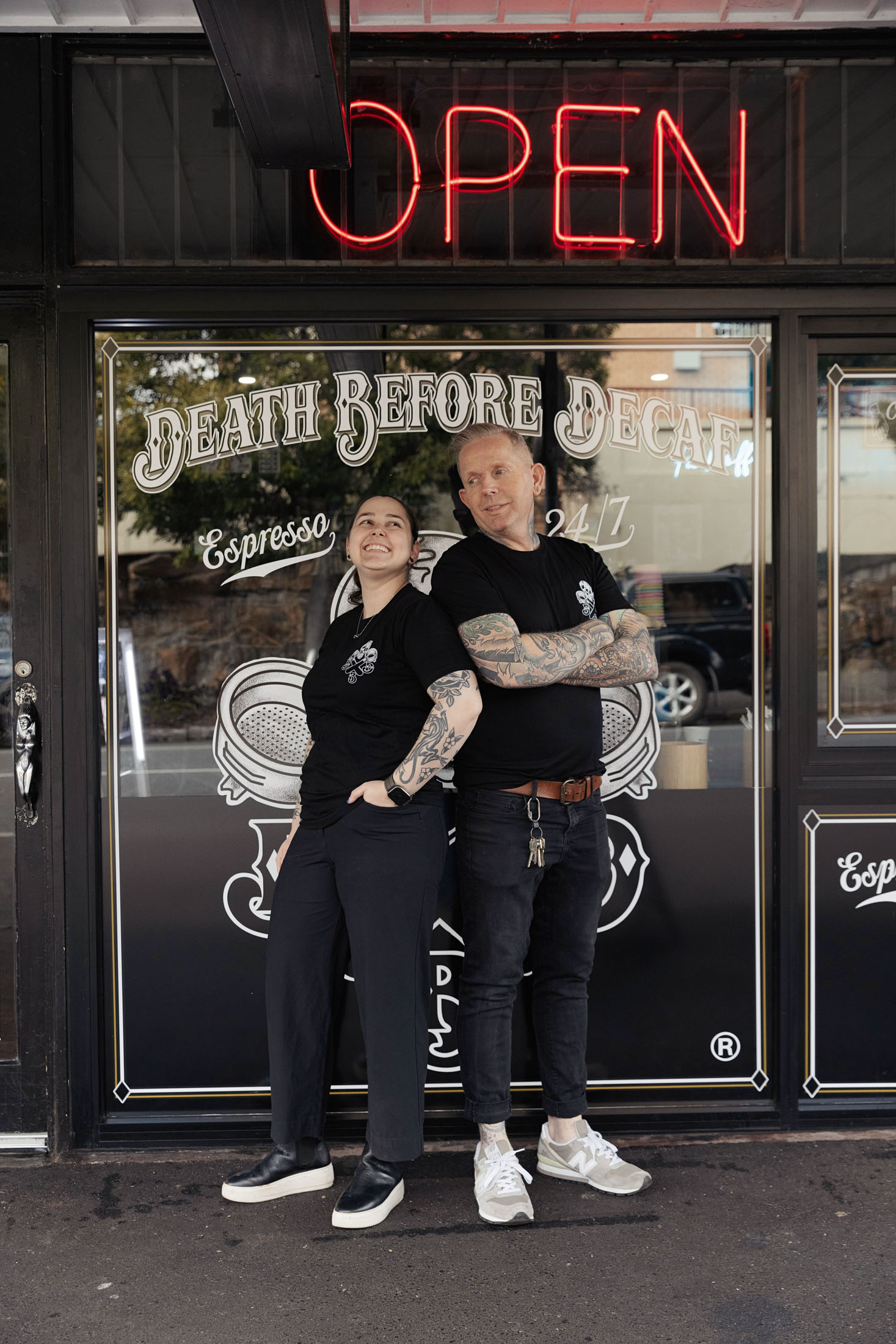 Two people standing outside a cafe with 'Death Before Decaf' sign.