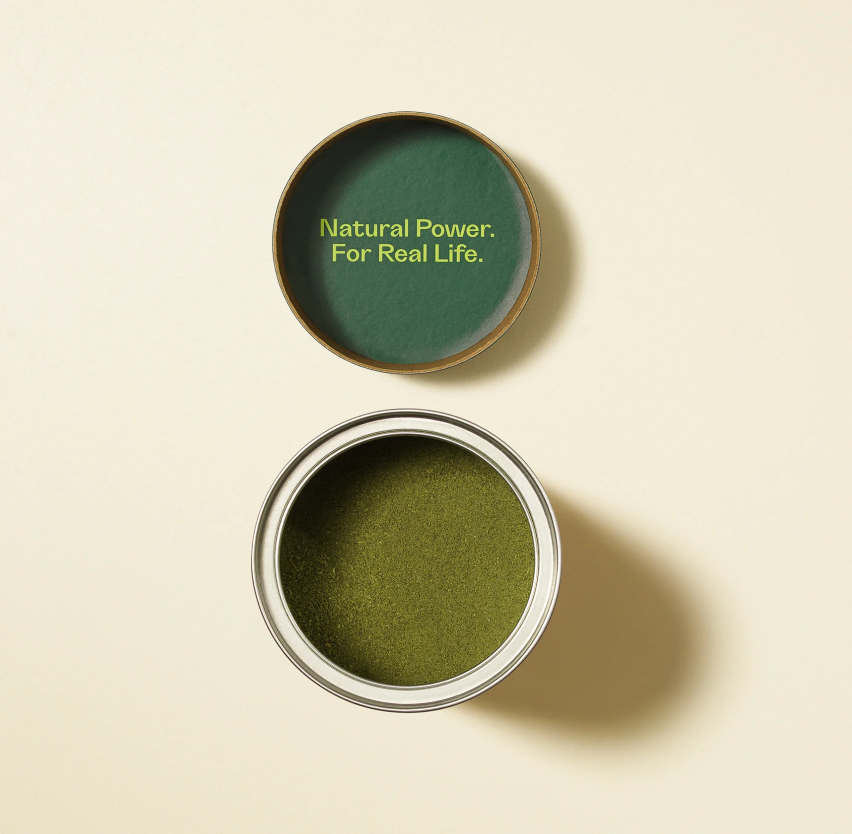 An open tin of green powder. The lid says 'Natural Power. For Real Life.'