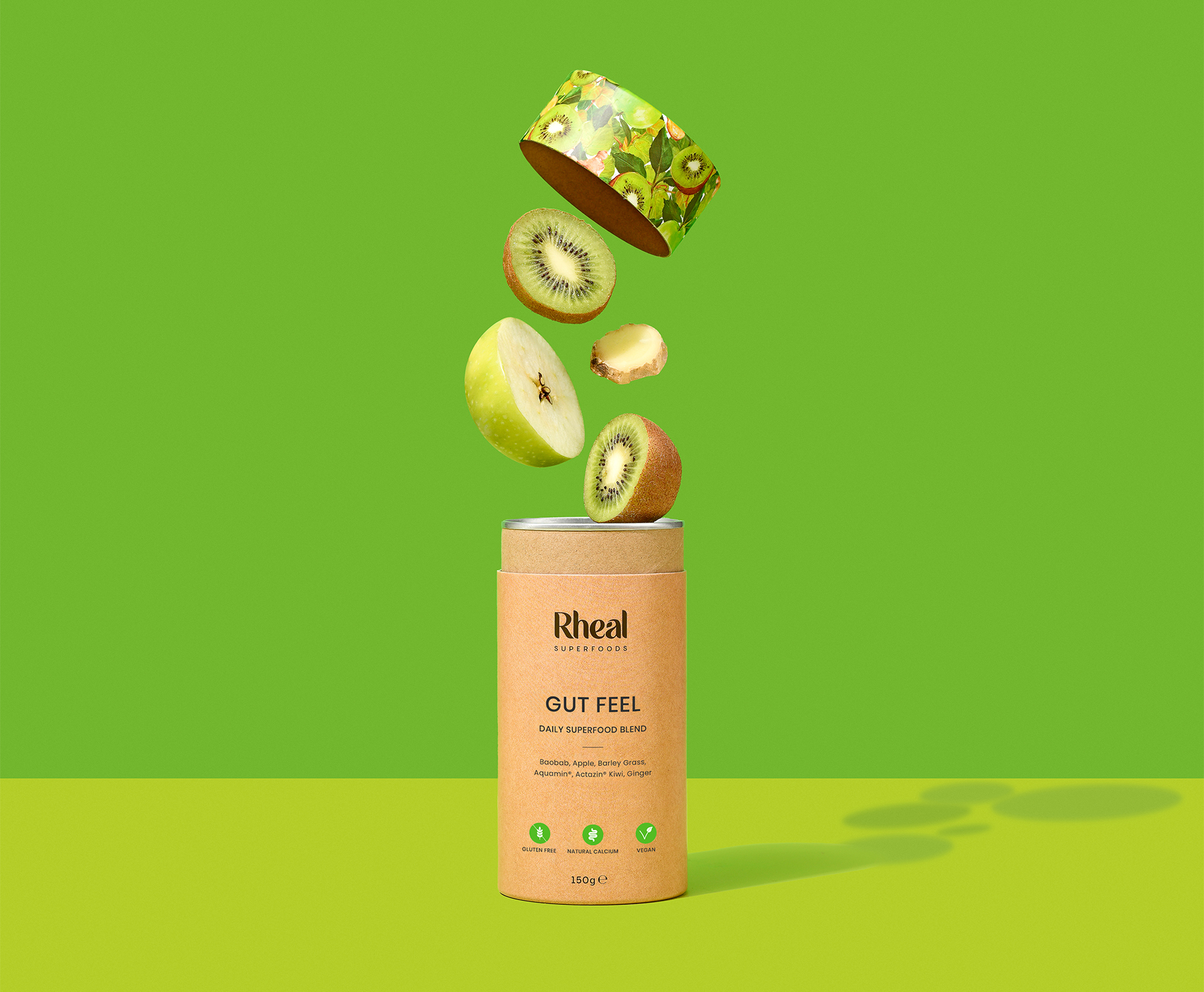 Floating fruits above a 'Rheal Superfoods Gut Feel' canister on a green background.